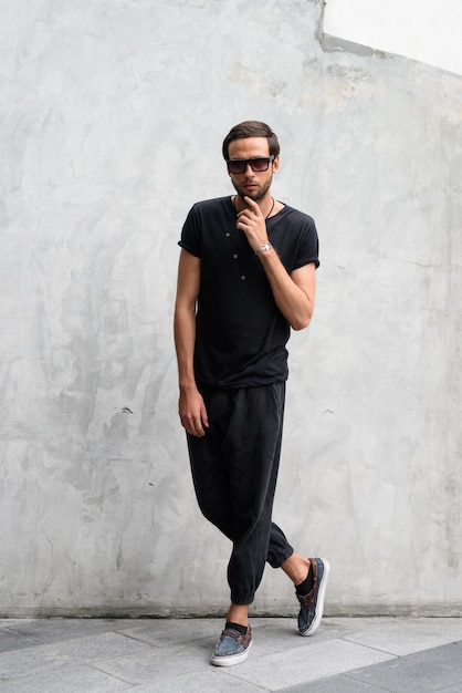 Handsome man wearing sunglasses against concrete wall in the streets outdoors