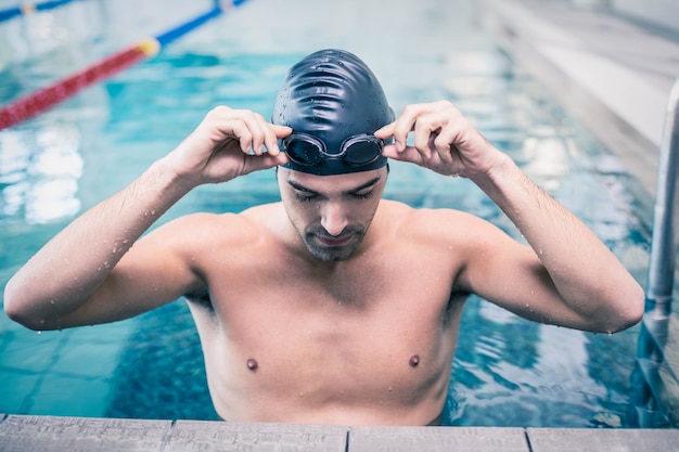 Handsome man wearing swim cap and goggles at the pool