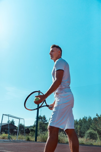 Handsome man wearing white shorts holding tennis racket