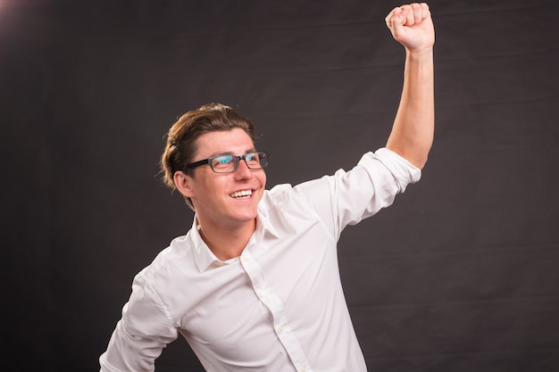 Handsome man in white shirt showing winning gesture on darkd.