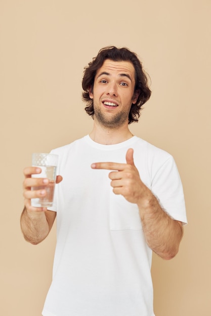 手にマグカップを持つ白いTシャツのハンサムな男ライフスタイルは変更されていません