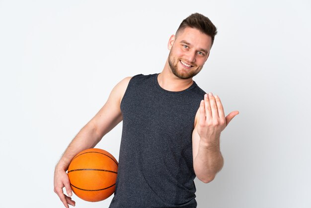 Bell'uomo sul muro bianco giocando a basket e facendo il gesto di venire