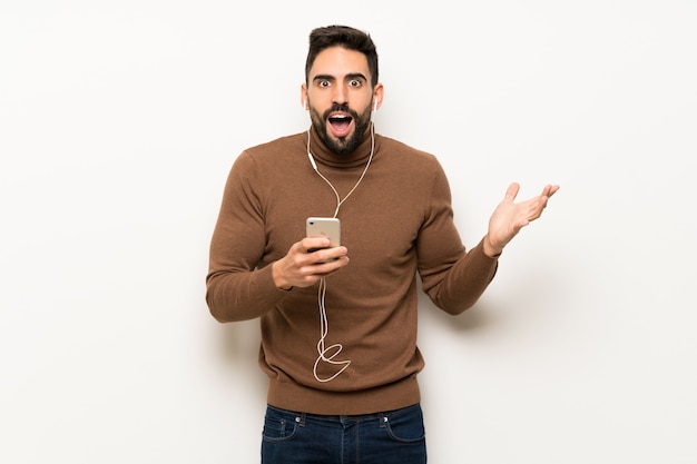 Handsome man over white wall surprised and sending a message