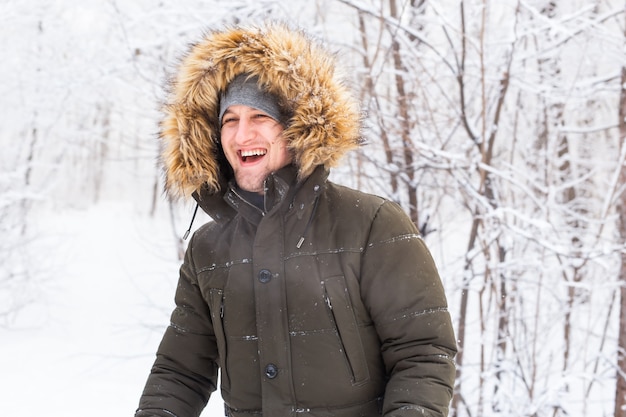 Handsome man in winter hat smiling portrait on snowy nature.