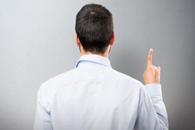 Handsome man with beard counting one on textured background