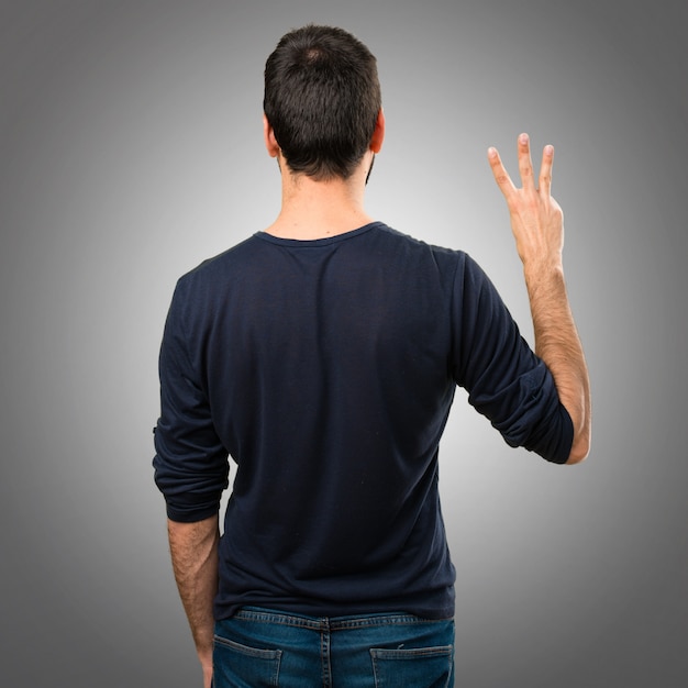 Handsome man with beard counting three on grey background