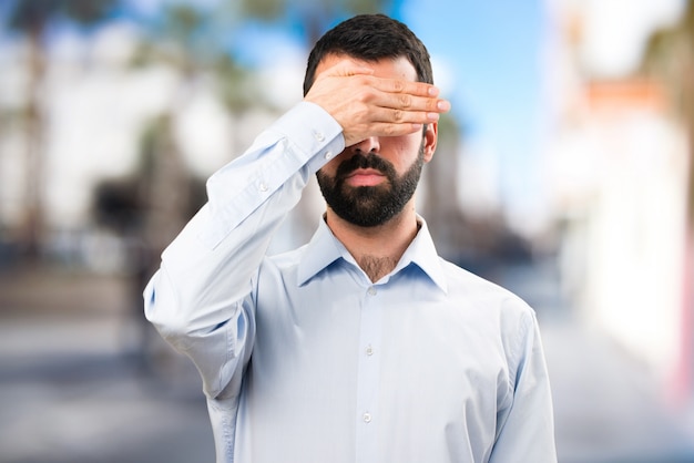 Foto uomo bello con la barba che copre gli occhi su sfondo unfocused