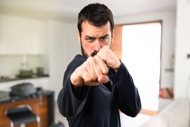 Foto uomo bello con la barba che combatte all'interno della casa