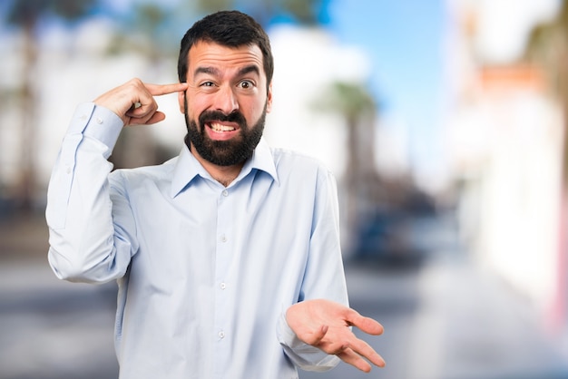 Handsome man with beard making crazy gesture on unfocused background