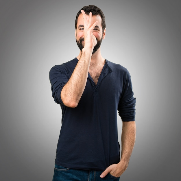 Handsome man with beard making a joke on grey background