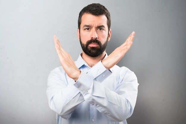 Handsome man with beard making NO gesture on textured background