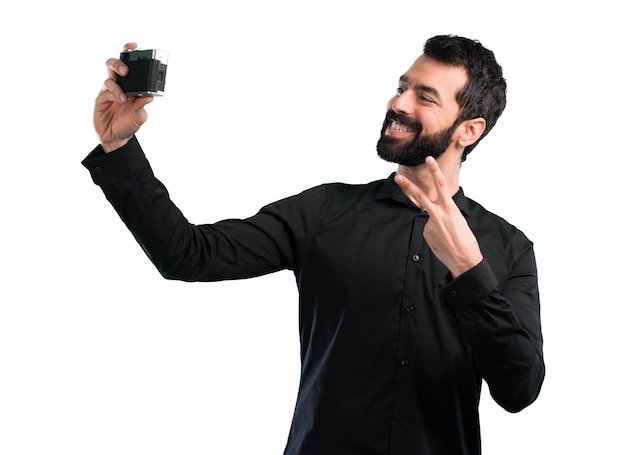 Uomo bello con la barba che fa un selfie su fondo bianco