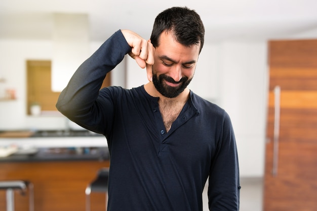 Handsome man with beard pointing down inside house