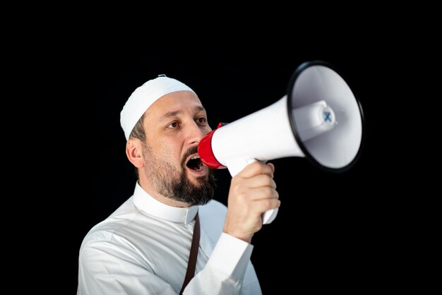 Uomo bello con la barba che grida attraverso il megafono per hajj in mekkah