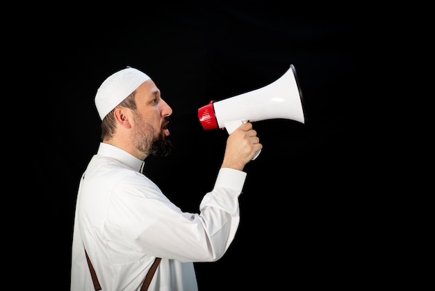 Uomo bello con la barba che grida attraverso il megafono per hajj in mekkah