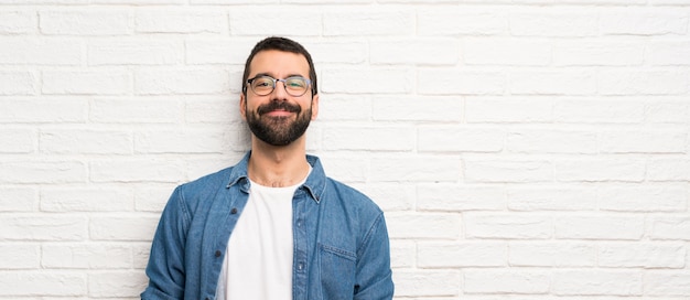 Uomo bello con la barba sopra la risata bianca del muro di mattoni