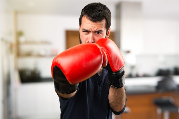 Handsome man with beard with boxing gloves inside house