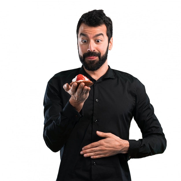 Handsome man with beard with pastry on white background