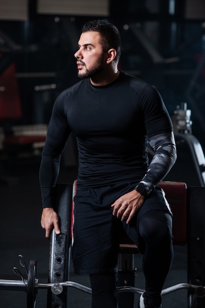 Handsome man with big muscles, posing at the camera in the gym