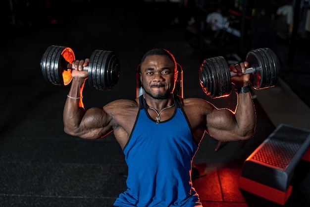 Handsome man with big muscles pumping in the gym. Young bodybuilder training biceps.