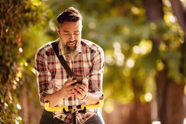 Photo handsome man with bike sending text message.