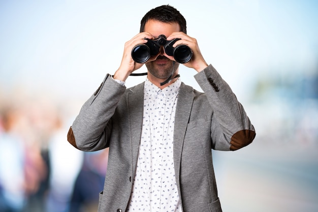 Handsome man with binoculars on unfocused background