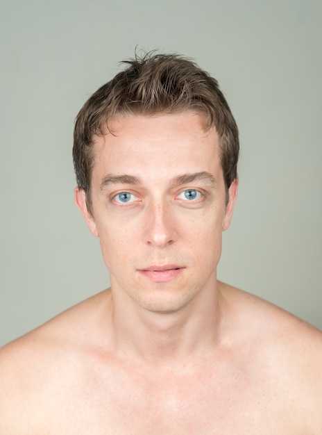  handsome man with brown hair shirtless against white wall