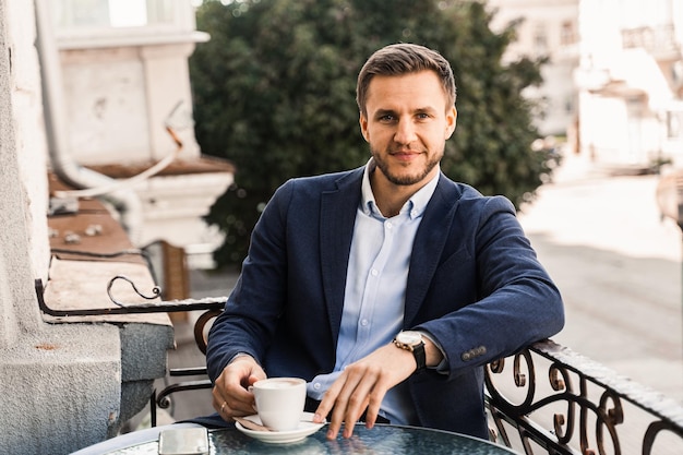 Handsome man with cup of coffee in cafe. Morning lifestyle of male.