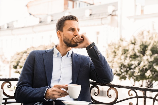 カフェでコーヒーを飲みながらハンサムな男。男性の朝のライフスタイル。