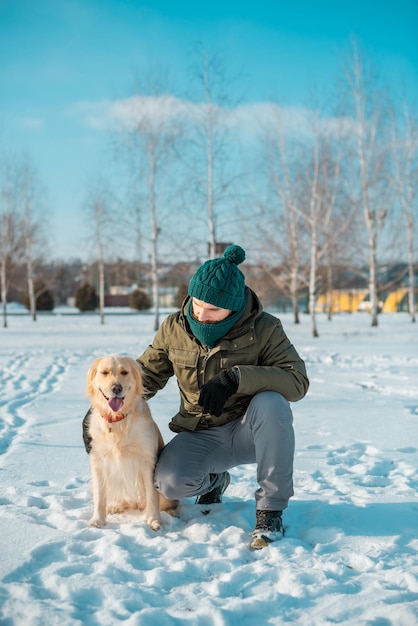 Handsome man with a dog golden retriever walk in spring\
meadow