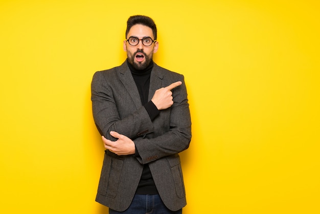 Handsome man with glasses surprised and pointing side