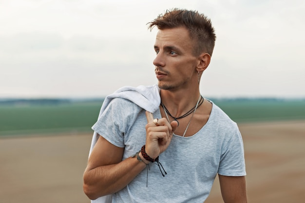 Handsome man with hair holds jacket on the of nature