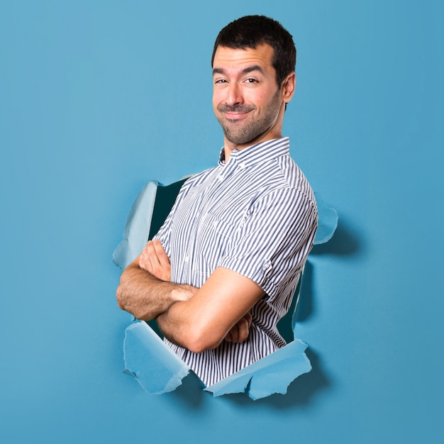 Handsome man with his arms crossed through a paper hole