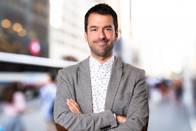 Handsome man with his arms crossed on unfocused background