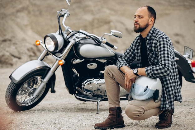 Handsome man with his moto in sand quarry