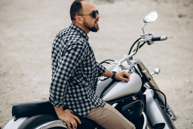 Handsome man with his moto in sand quarry