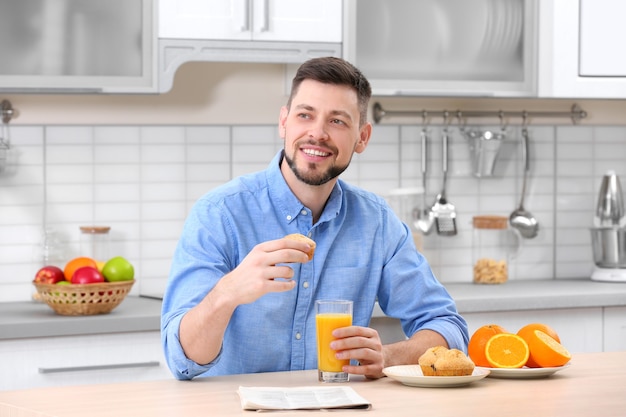 Bell'uomo con succo in cucina