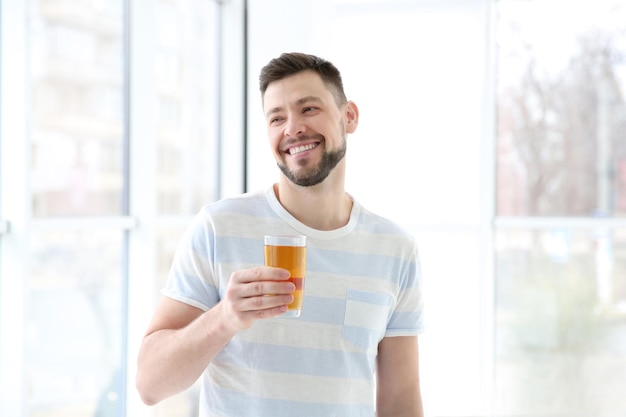 Handsome man with juice standing near window