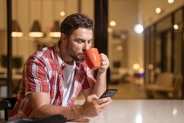 Handsome man with mobile phone sitting on weekend at home american man using phone while sitting on