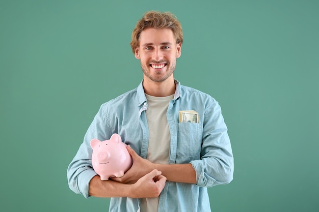 Handsome man with piggy bank on green