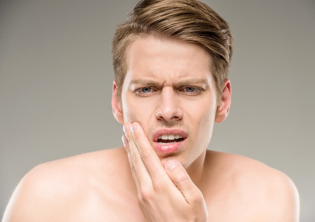 Handsome man with pure skin touching his face.