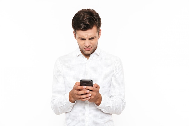 Handsome man with short dark hair chatting or typing text message holding mobile phone