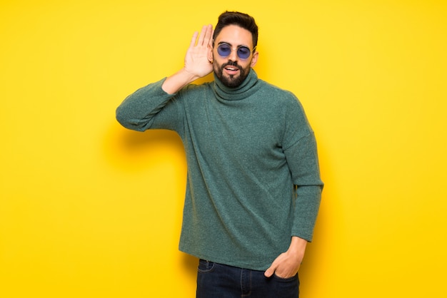 Handsome man with sunglasses listening to something by putting hand on the ear