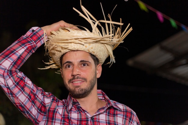 Handsome man with typical festa junina clothes smiling at the festa junina