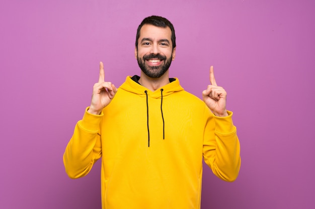 Handsome man with yellow sweatshirt pointing up a great idea