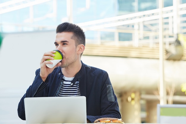 Красивый человек, работающий в кафе на ноутбуке, пить кофе