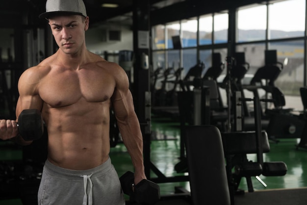 Handsome Man Working Out Biceps In A Dark Gym  Dumbbell Concentration Curls