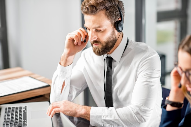 Bell'uomo che lavora con auricolare e laptop al call center