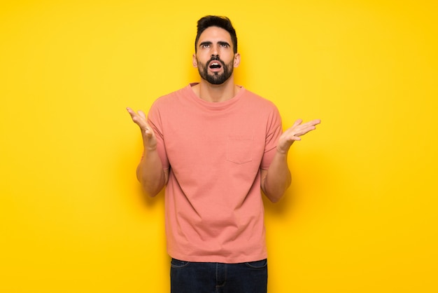 Handsome man over yellow wall frustrated by a bad situation