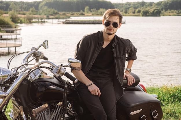 Handsome man or young biker sitting and chilling on the bike chopper outdoors